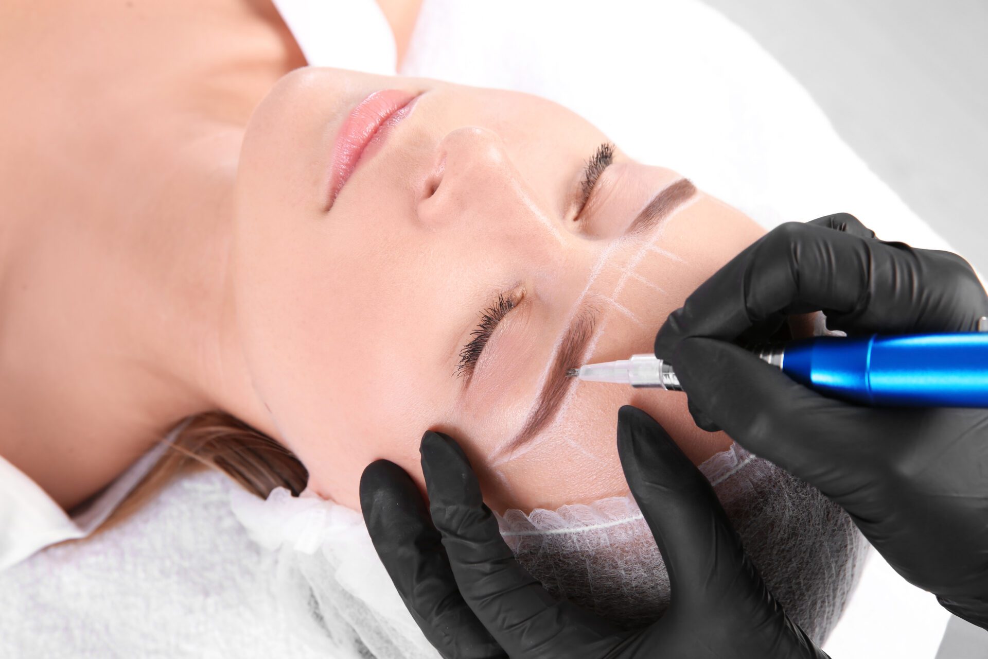 Young woman undergoing eyebrow correction procedure in salon